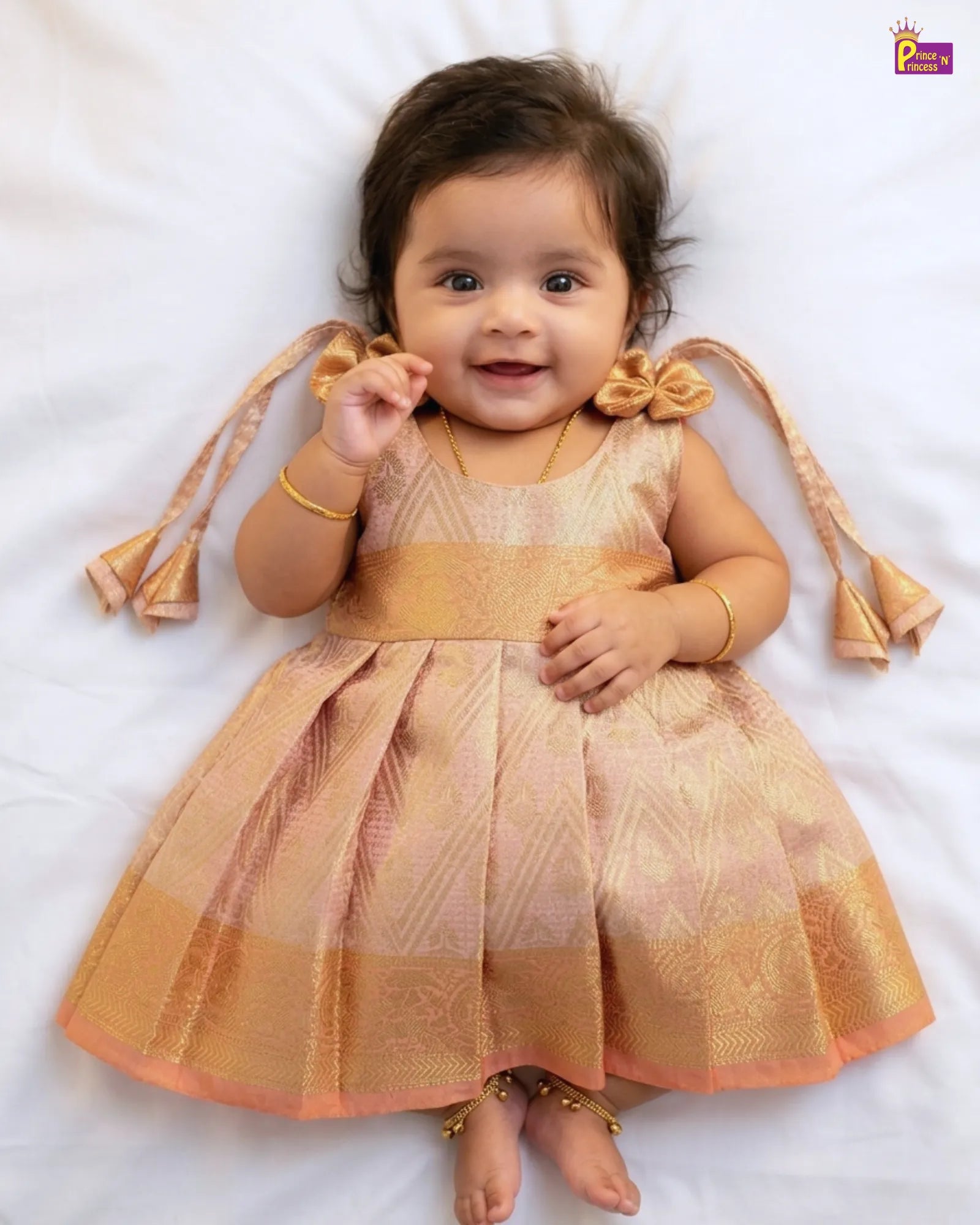 Baby wearing a gold dress with decorative elements on a white background
