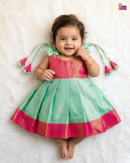 Baby wearing a pink and green traditional outfit on a white background