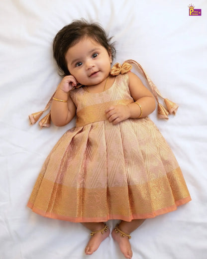 Baby in a gold dress lying on a white surface