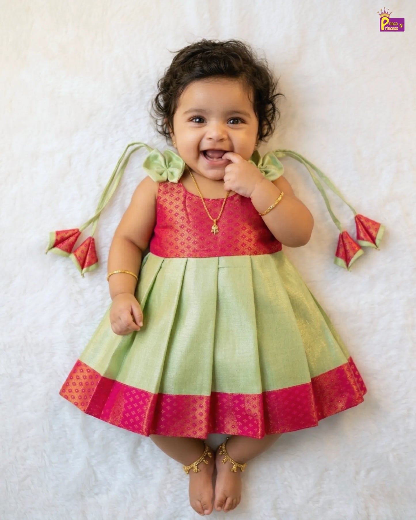 Baby wearing a red and green traditional outfit on a white background