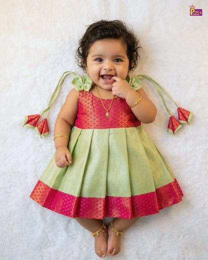 Baby wearing a red and green traditional outfit on a white background