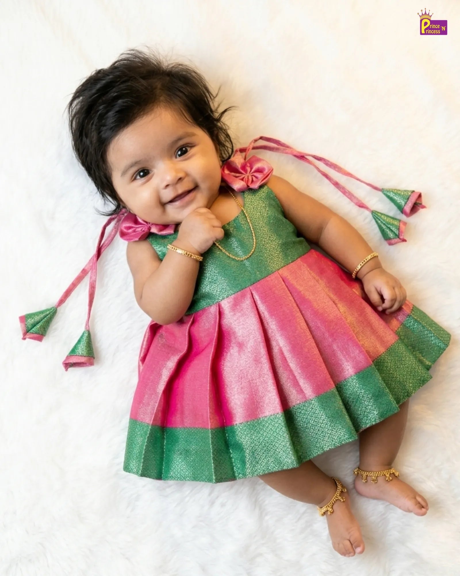 Baby wearing a colorful traditional outfit with pink and green dress on a white background