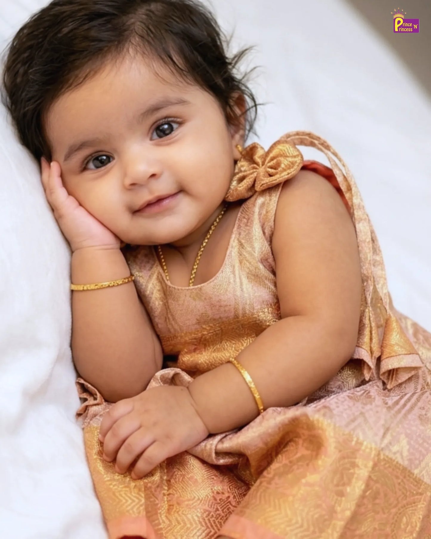 Baby in a traditional outfit with gold accents on a white background