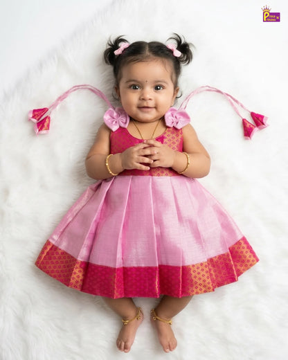 Young child wearing a pink and red dress with decorative elements on a white background