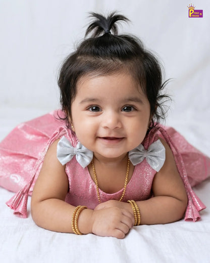 Baby in a pink outfit with bows on a white background