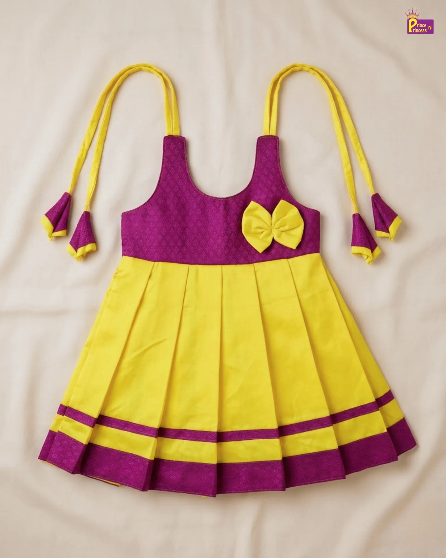 Baby in a purple and yellow outfit lying on a white surface