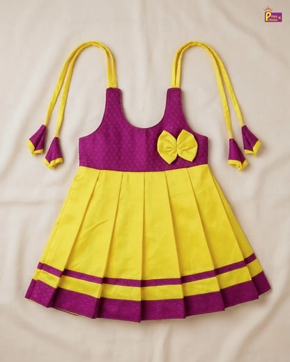 Baby in a purple and yellow outfit lying on a white surface