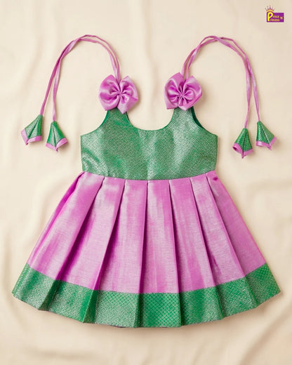 Green and pink children's dress with floral headbands on a beige background
