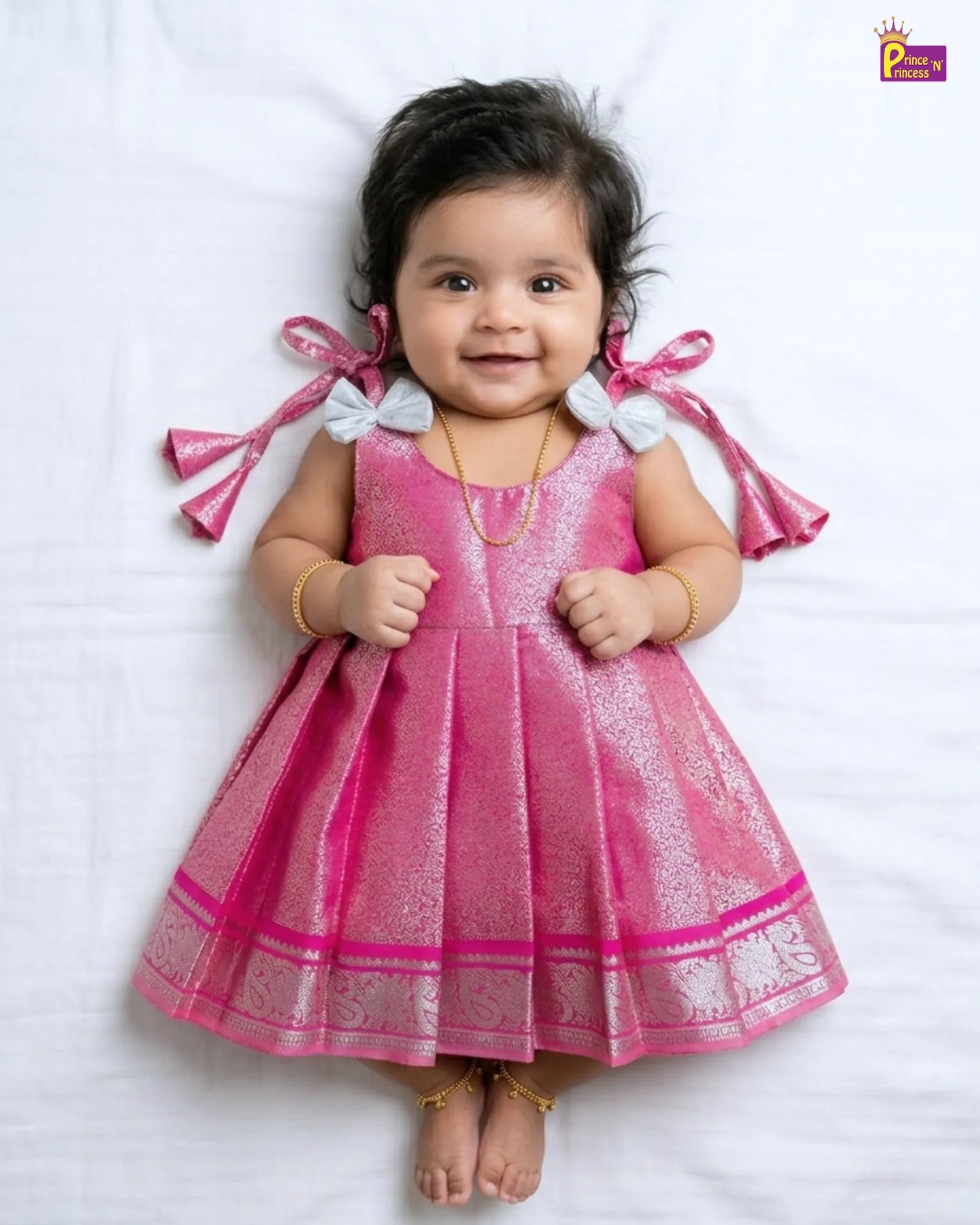 Baby wearing a pink dress with white details on a white background