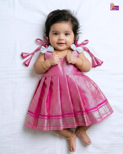 Baby wearing a pink dress with white patterns on a white background