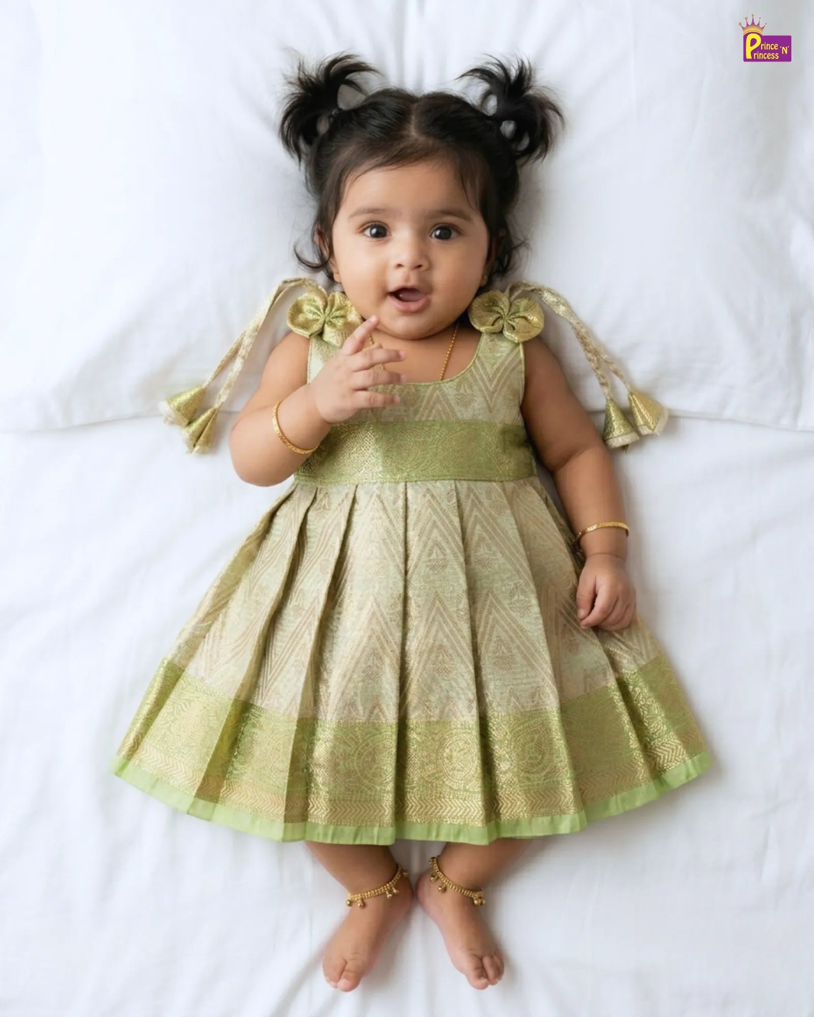 Baby wearing a green dress with decorative elements on a white background