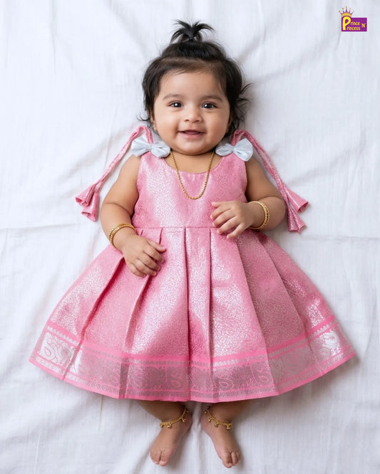 Baby wearing a pink dress with white floral details on a white background