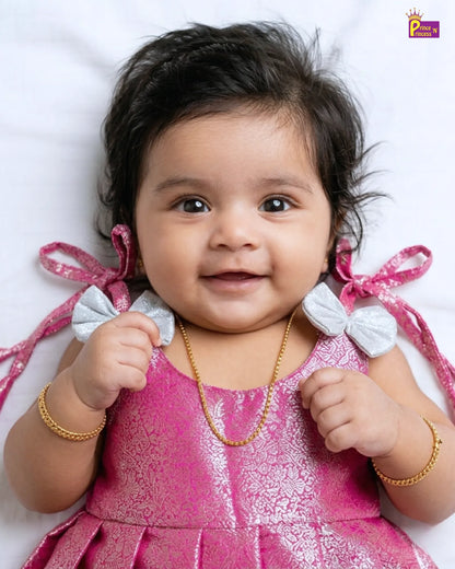 Baby in a pink dress with decorative ribbons on a white background