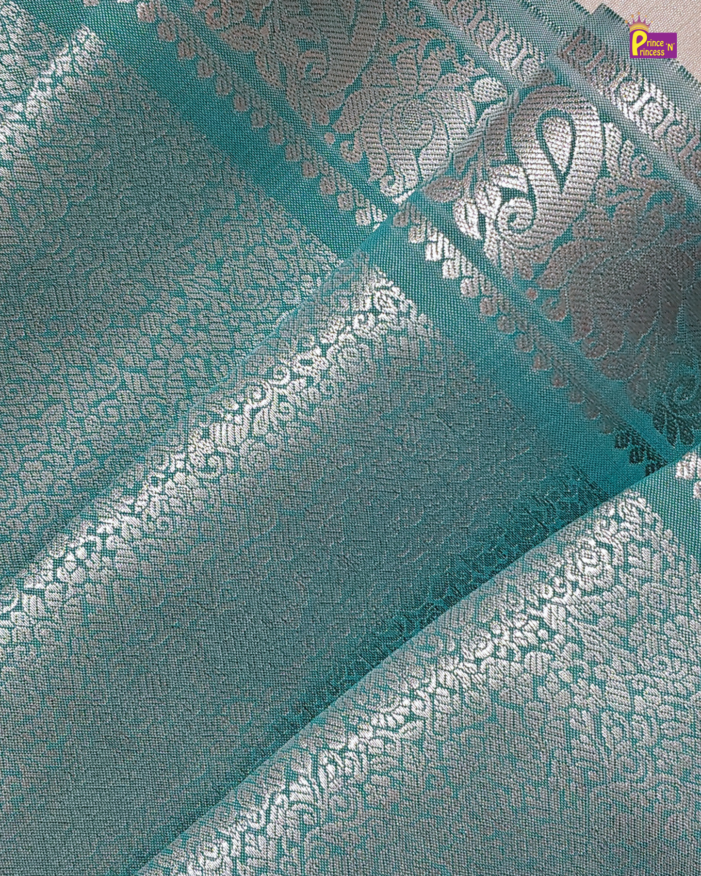 Teal fabric with silver floral patterns and a brand logo in the corner.
