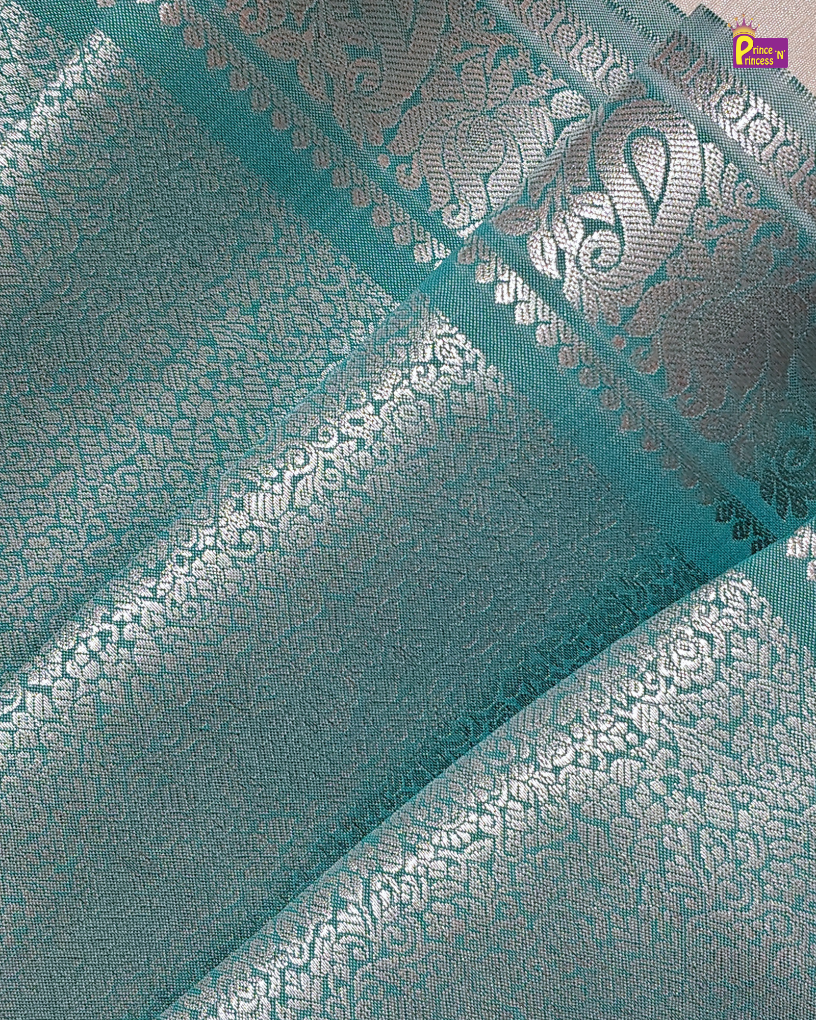 Teal fabric with silver floral patterns and a brand logo in the corner.