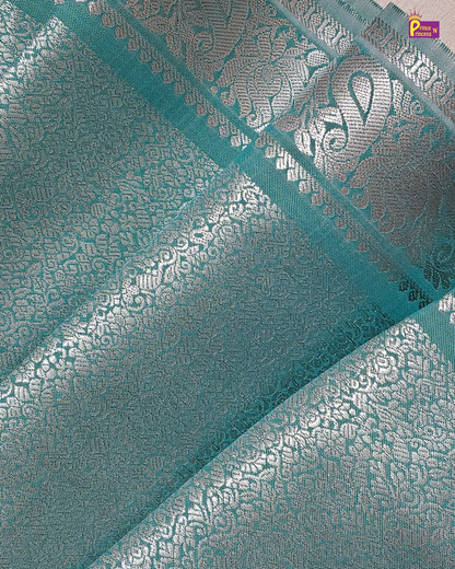 Teal fabric with silver floral patterns and a brand logo in the corner.