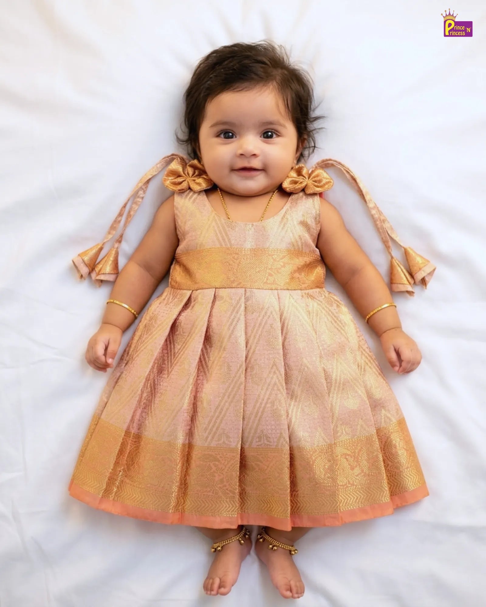 Baby wearing a traditional outfit with gold and pink colors on a white background