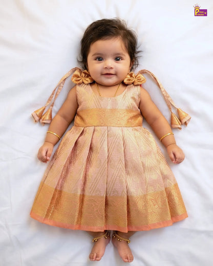 Baby wearing a traditional outfit with gold and pink colors on a white background