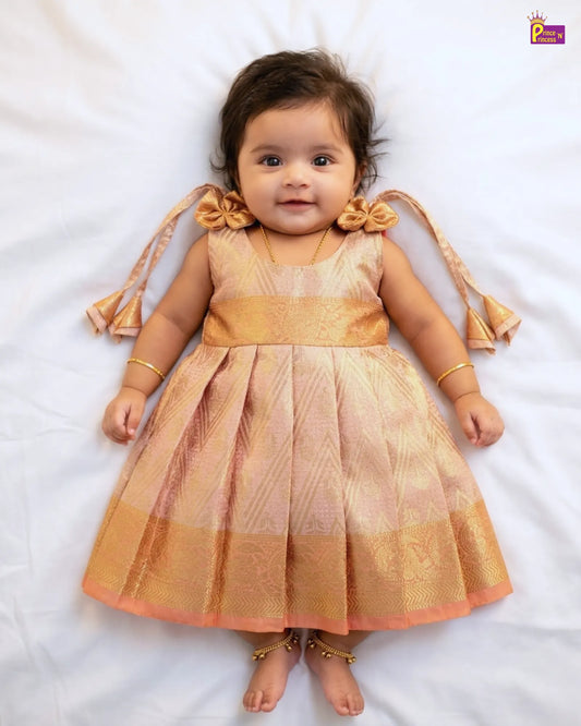 Baby wearing a traditional outfit with gold and pink colors on a white background