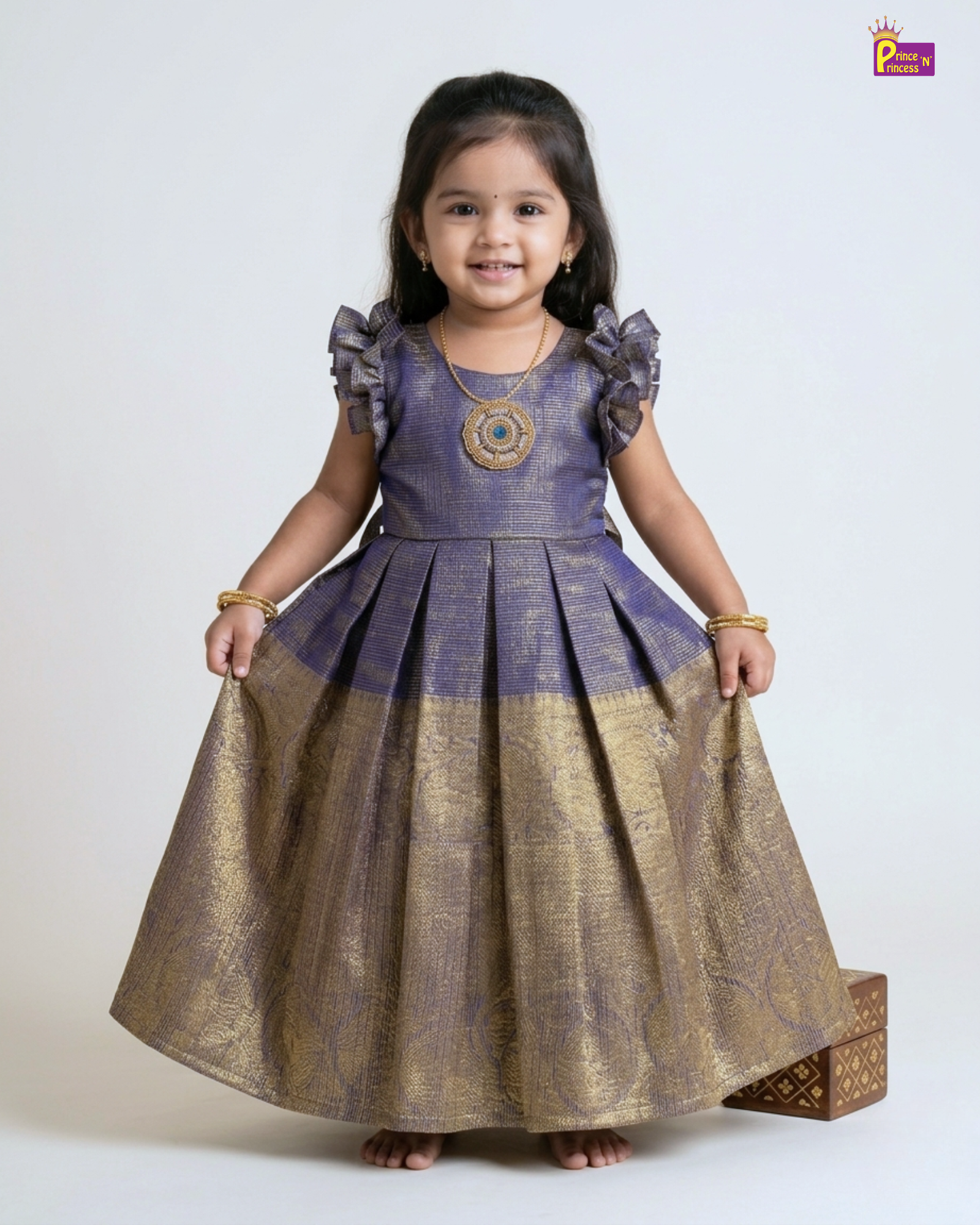 Young girl wearing a traditional outfit with a purple top and gold skirt on a white background