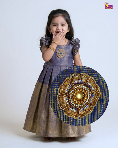 Young girl wearing a traditional outfit with a decorative gold and blue design on a white background
