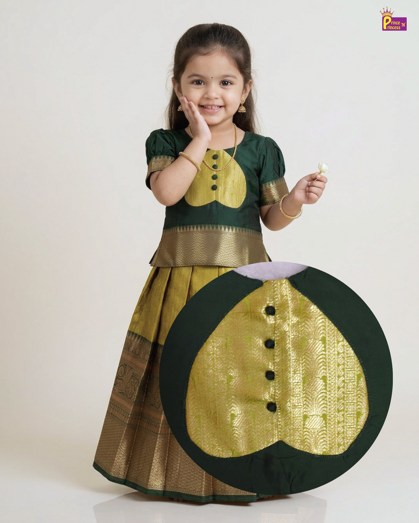 A young girl modeling a traditional Indian dress, featuring a dark green top with a gold embroidered chest motif and a matching pleated skirt with gold borders. A large circular inset highlights the detailed gold embroidery on the dress.