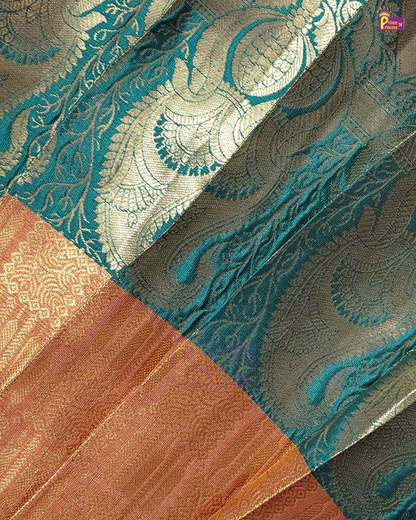 A close-up of a woven fabric with a teal blue and metallic gold paisley pattern, alongside a contrasting peach and gold border section.