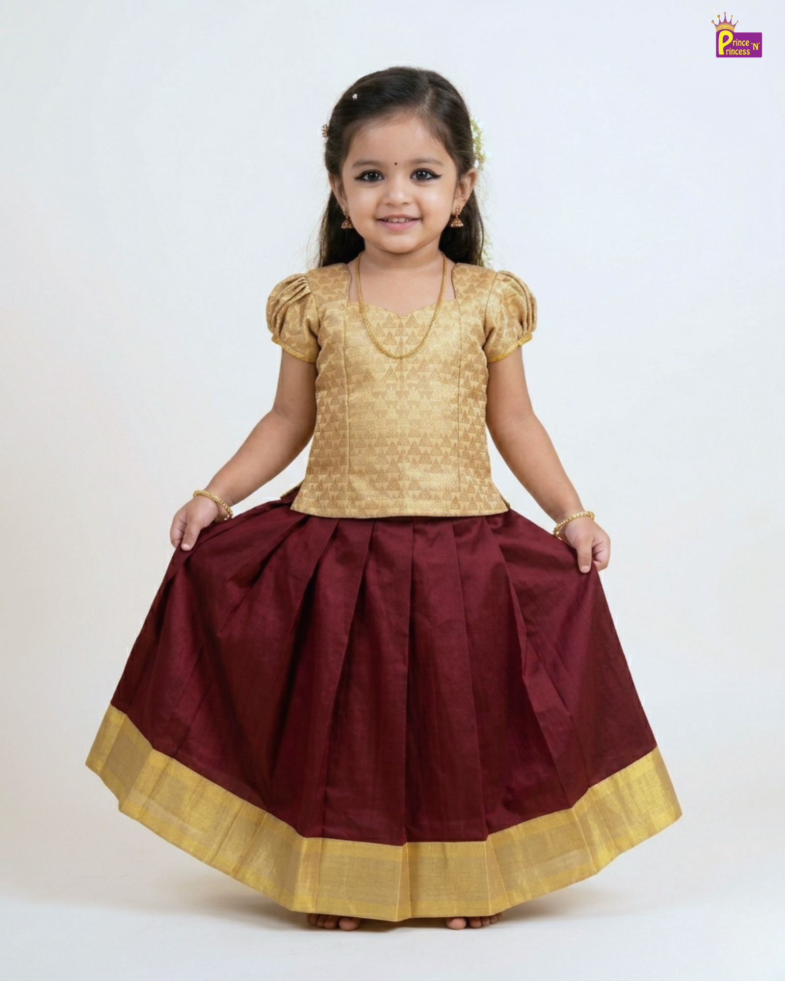 Young girl wearing a gold top and maroon skirt with gold trim on a white background