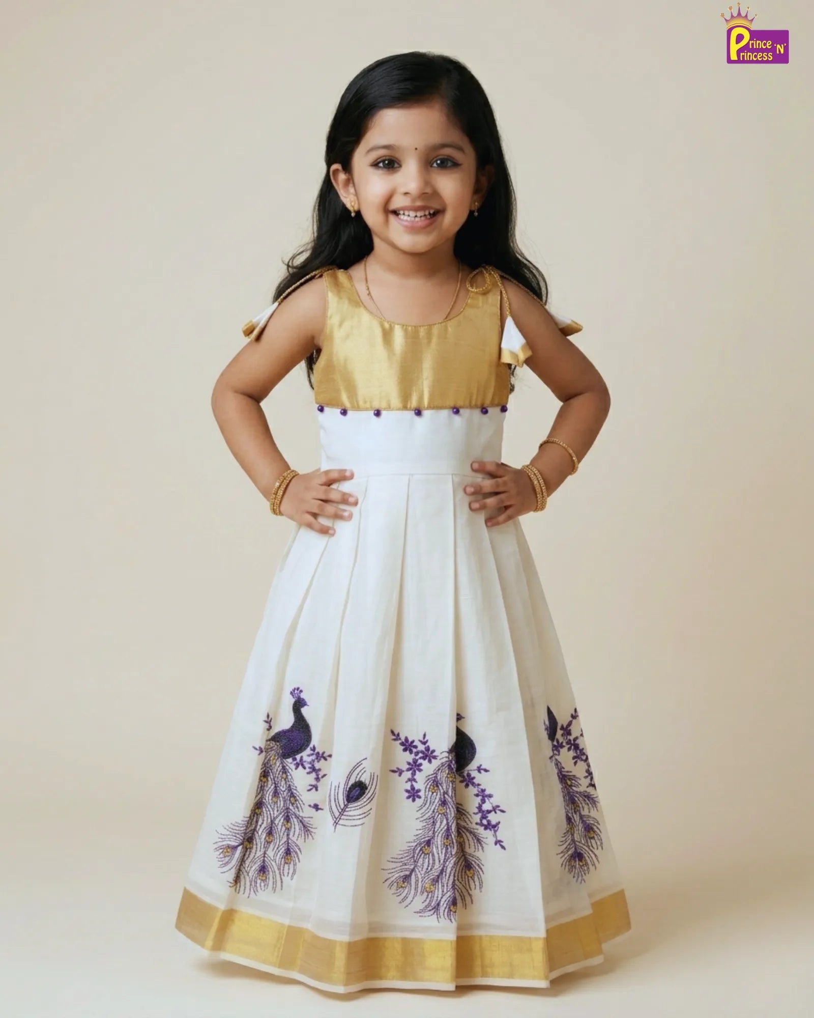 Young girl wearing a white dress with gold and purple accents, standing against a plain background.