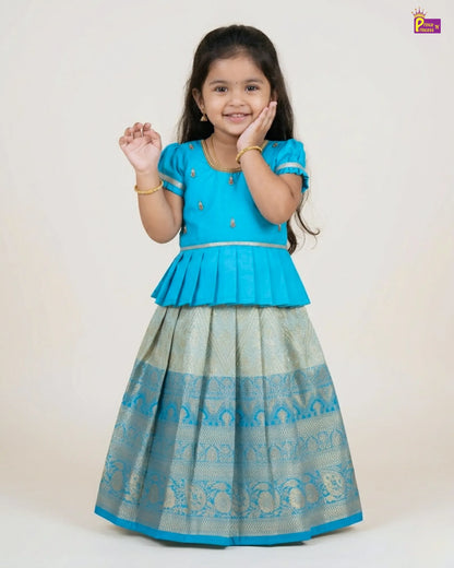 Young girl wearing a blue top and patterned skirt on a white background