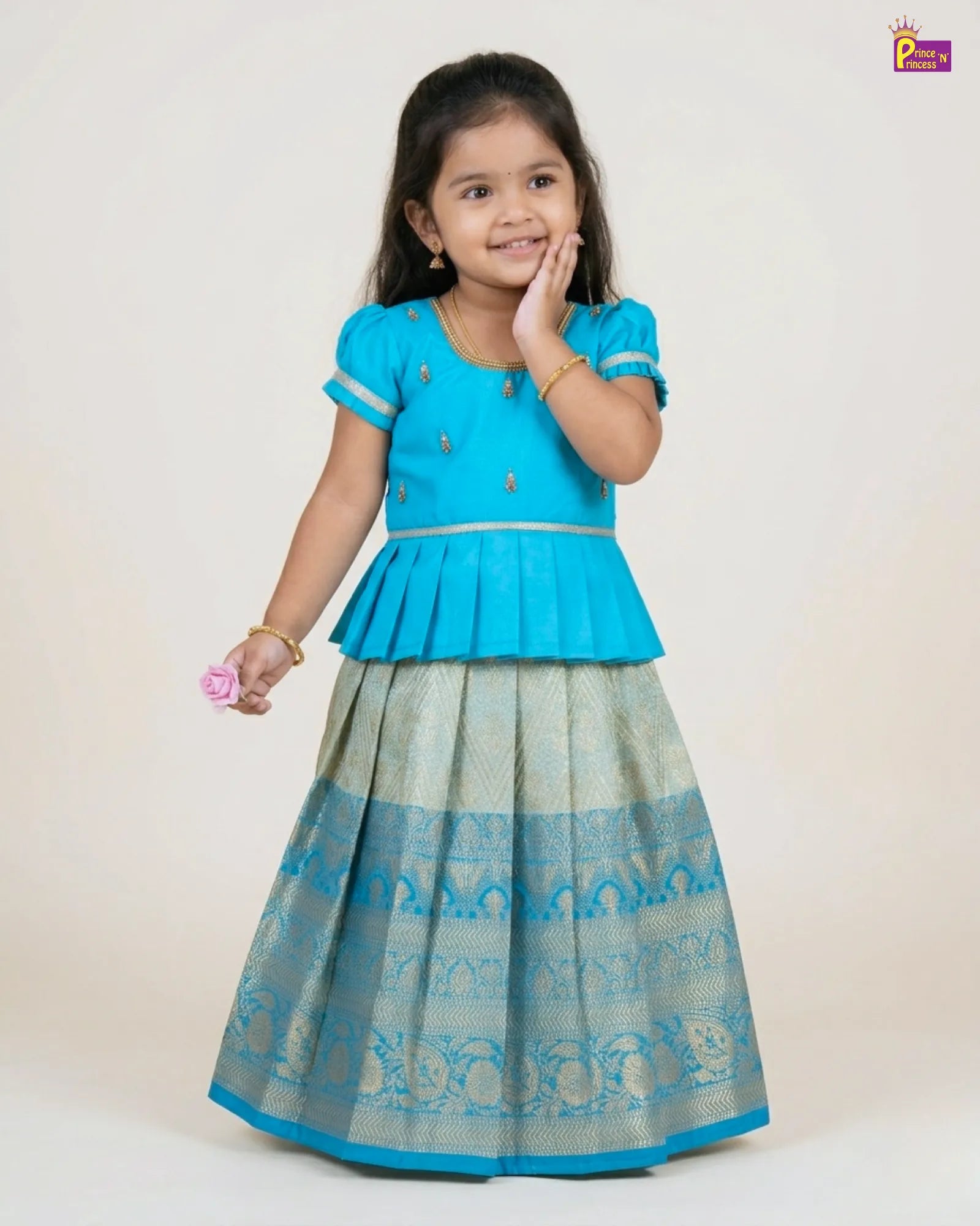 Young girl wearing a blue top and patterned skirt on a white background