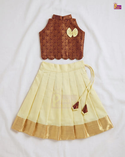 A two-piece children's traditional outfit laid flat on a white fabric background. The top is a sleeveless brown embroidered vest with a scalloped hem and a yellow bow accent.