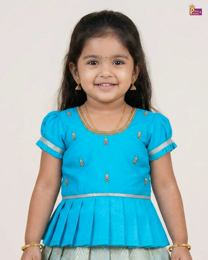 Young girl wearing a blue traditional outfit with gold details on a white background