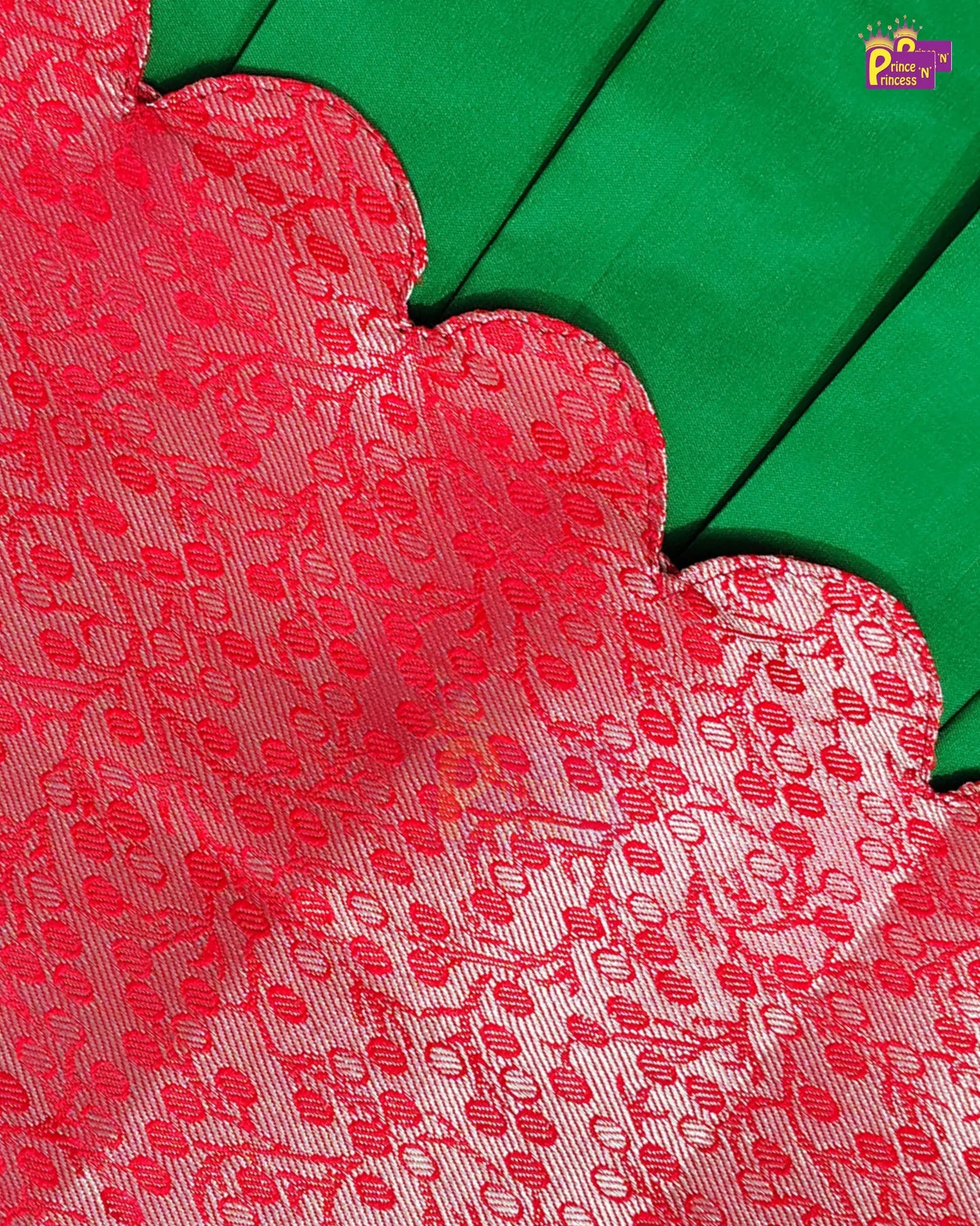 Close-up of a red and white patterned fabric with a scalloped edge, layered over a solid green fabric.