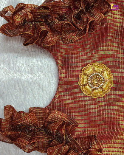 Brown fabric with decorative gold flower and ruffled edges on a white background