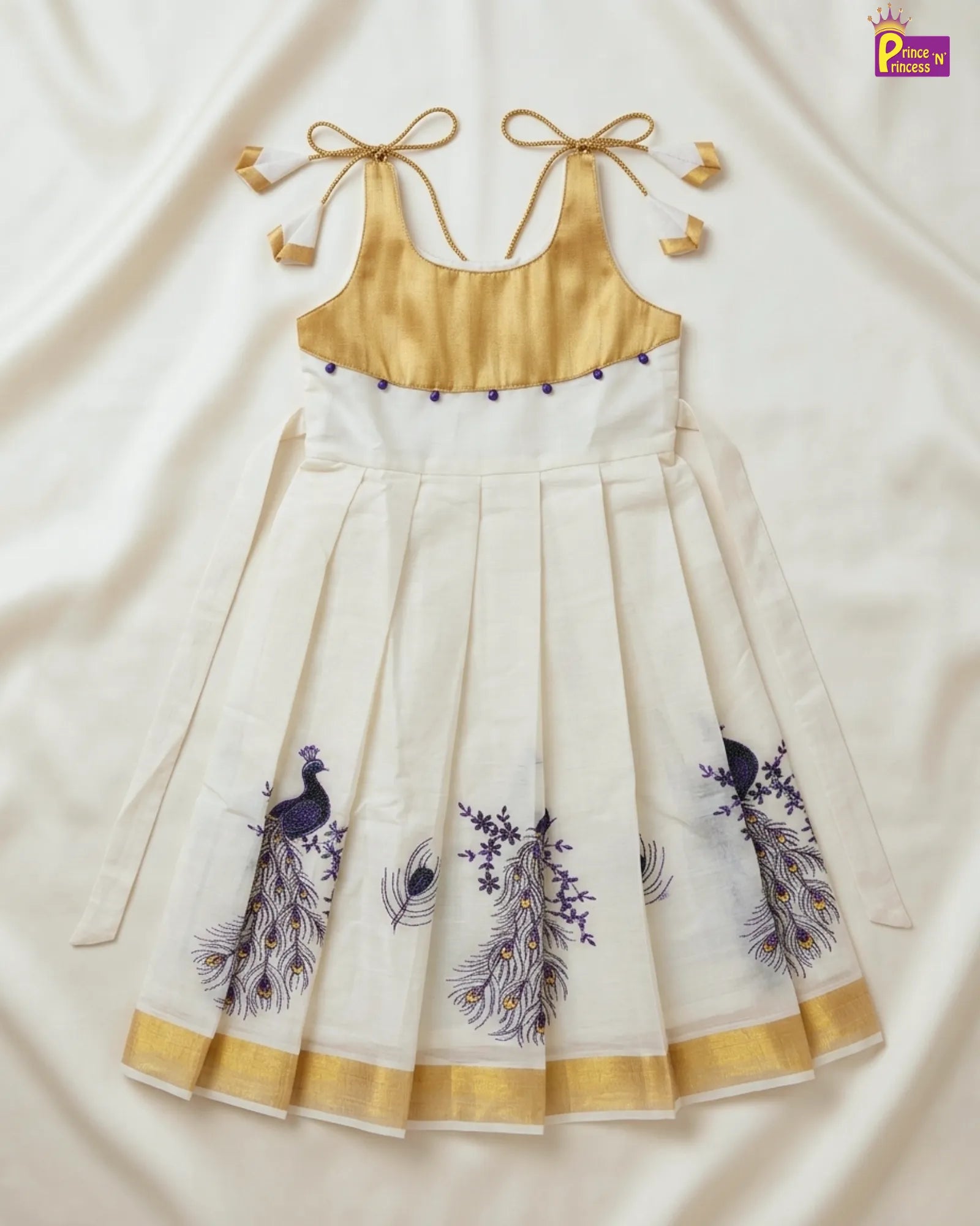 White dress with gold accents and peacock designs on a white background
