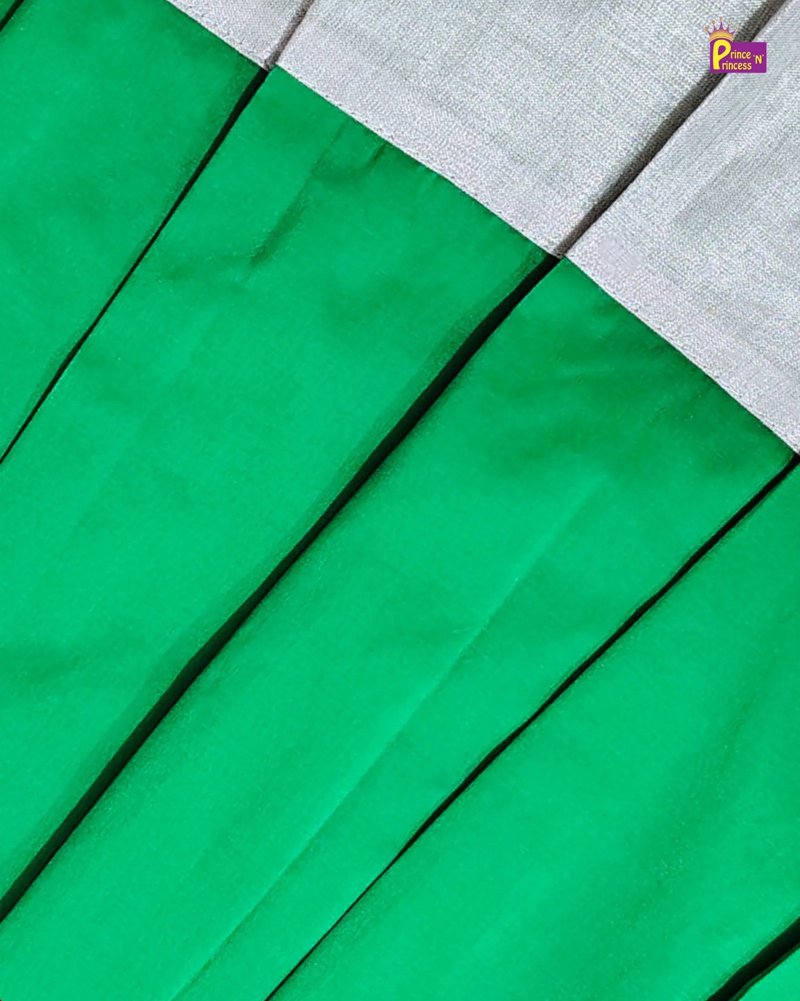 A close-up of a green pleated fabric, likely a skirt or drape, with a contrasting light gray textured border at the top. A small 'Puneera Fabrics' brand logo is visible in the upper right corner.
