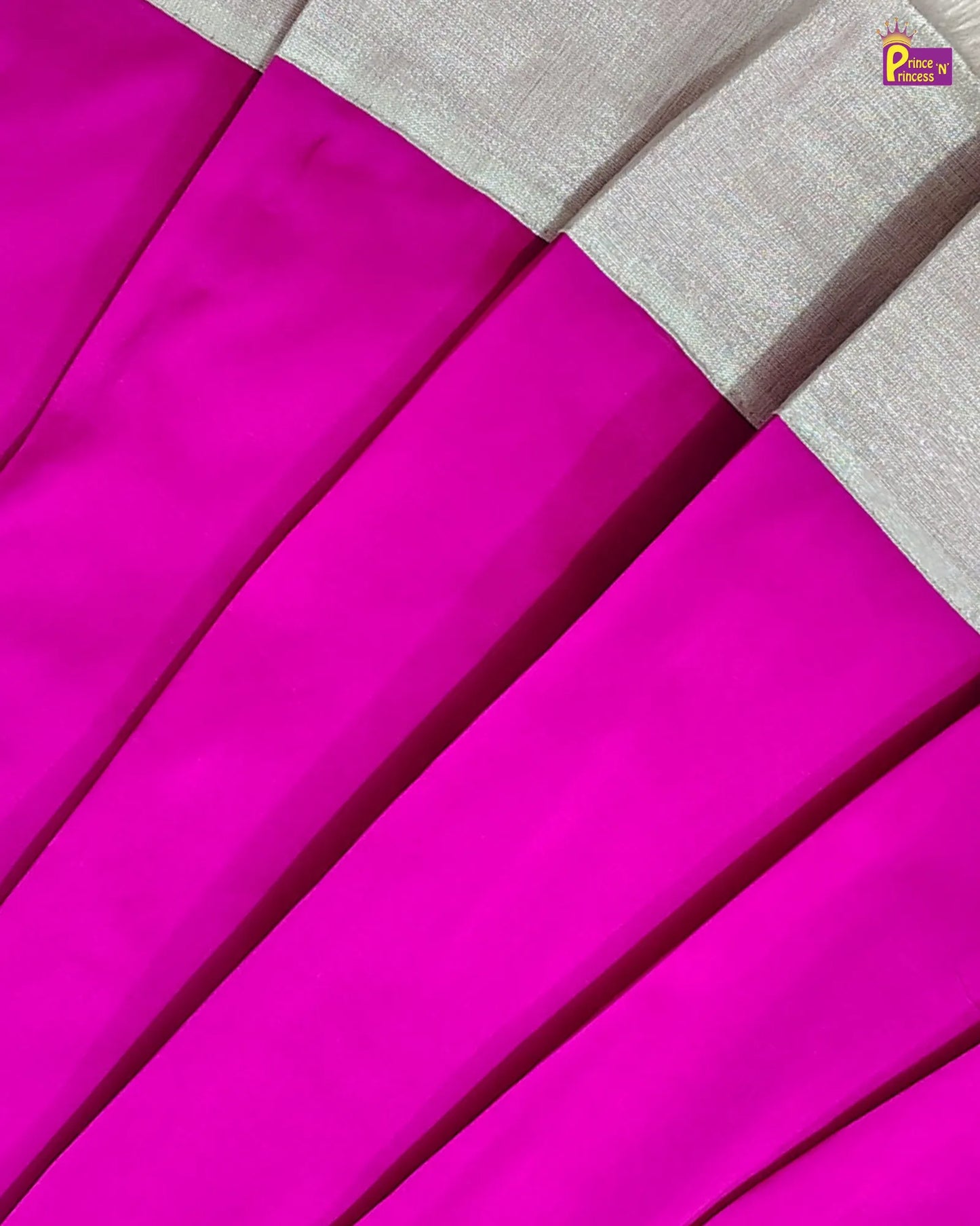 A close-up of a pleated fabric garment in vivid hot pink with a contrasting light beige border along the top edge.