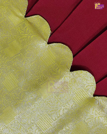 A close-up of a fabric product showing a yellow-gold scalloped border with a subtle woven floral pattern, layered over a deep red background.