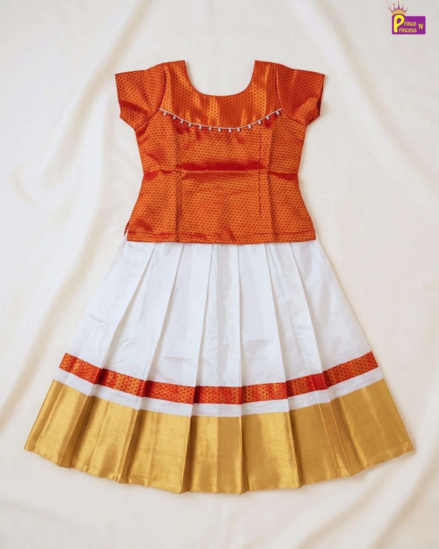 Traditional outfit with orange top, white skirt, and gold border on a light background