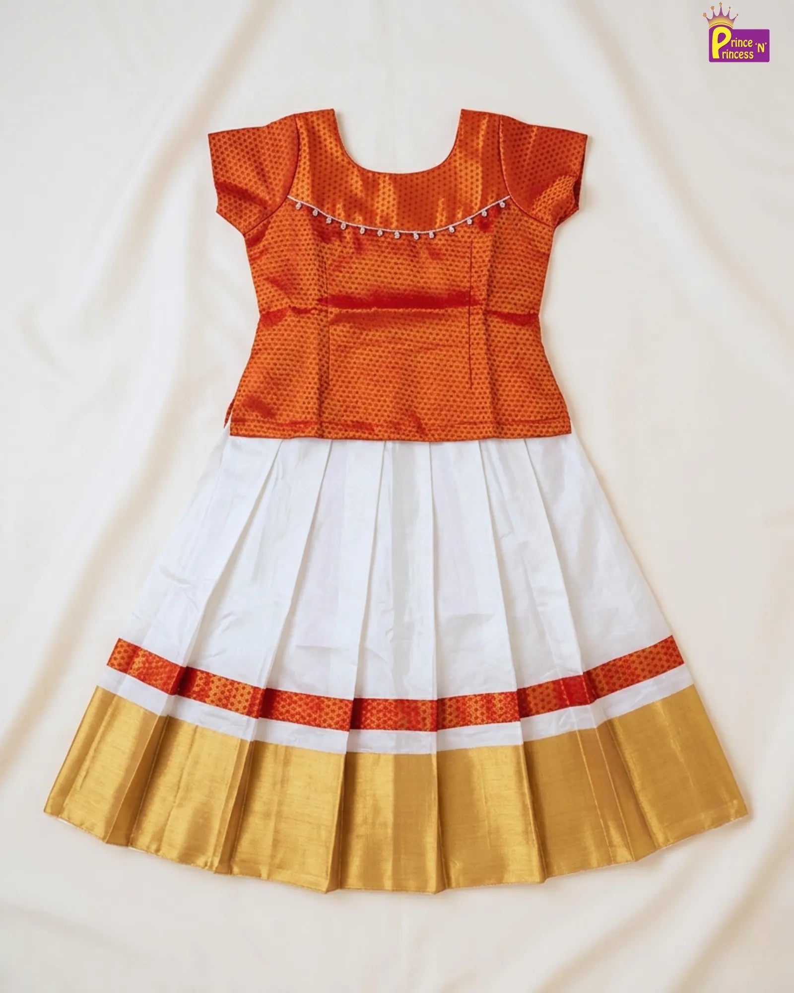 Traditional outfit with orange top, white skirt, and gold border on a light background
