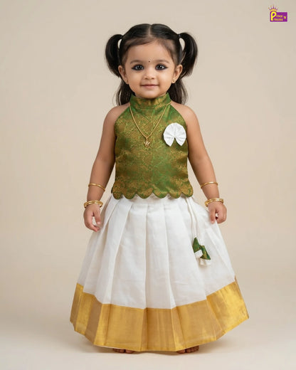 Child wearing a green and white traditional outfit with gold accents on a beige background