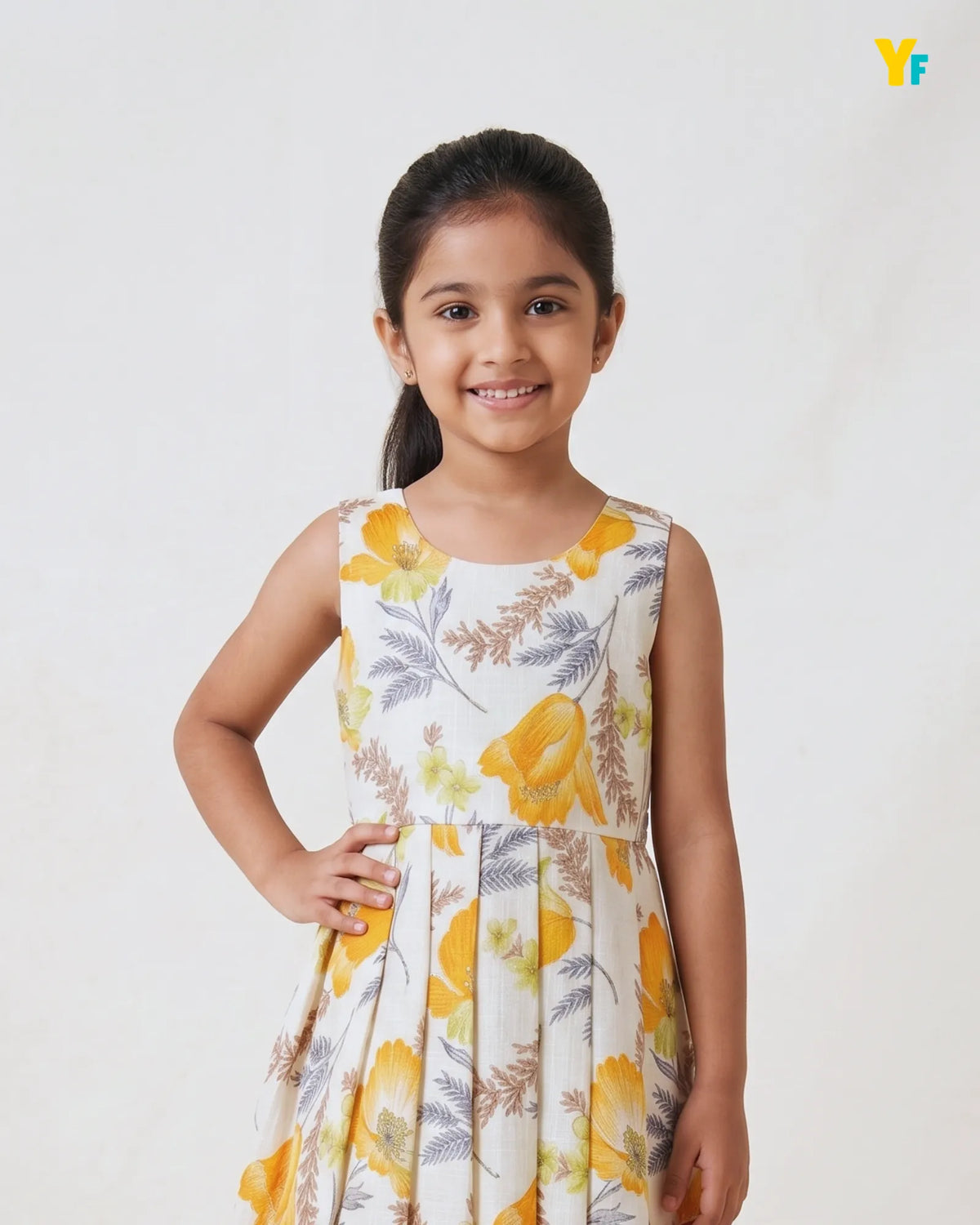 A young girl with dark hair tied back in a ponytail, wearing a sleeveless white dress with a yellow and gray floral print, posing against a light off-white background.