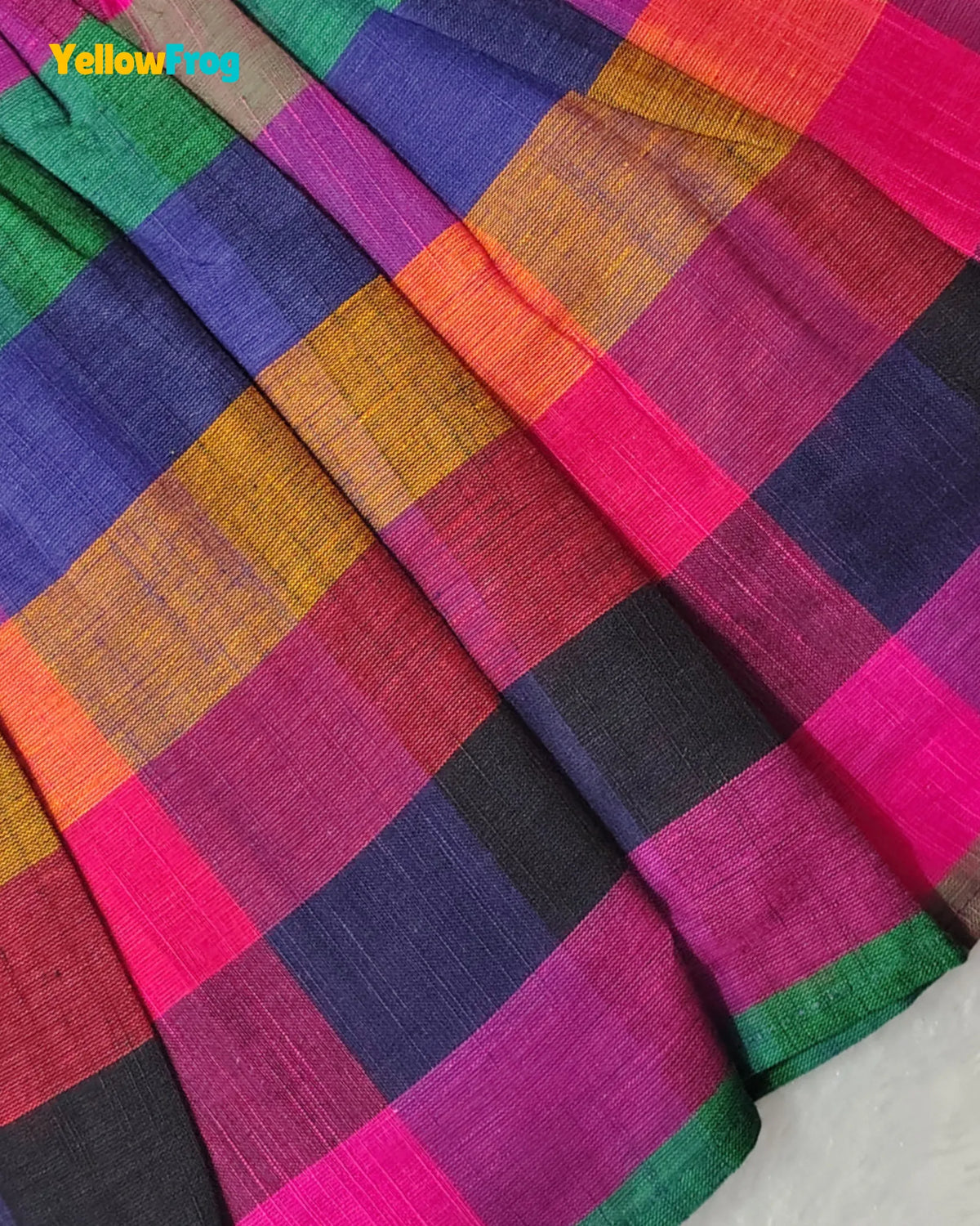 A close-up of a colorful plaid fabric with a textured weave, featuring blocks of magenta pink, purple, orange, green, black, and red. A yellow 'Yellow.