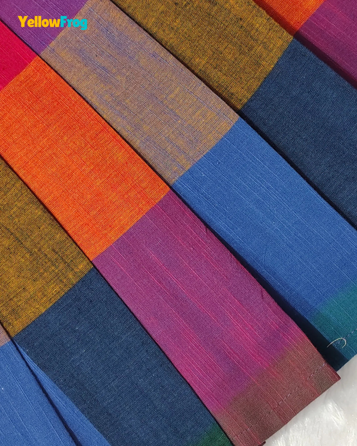 A close-up of a colorful striped fabric with textured woven stripes in orange, magenta, blue, navy, and mustard yellow. A 'YellowFrog' brand logo is visible in the top-left corner.
