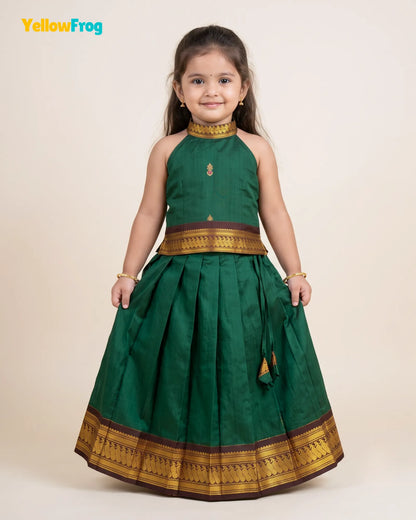 A young girl modeling a dark green traditional Indian dress with gold and brown borders, standing against a plain beige background. The YellowFrog logo is visible in the top left corner.