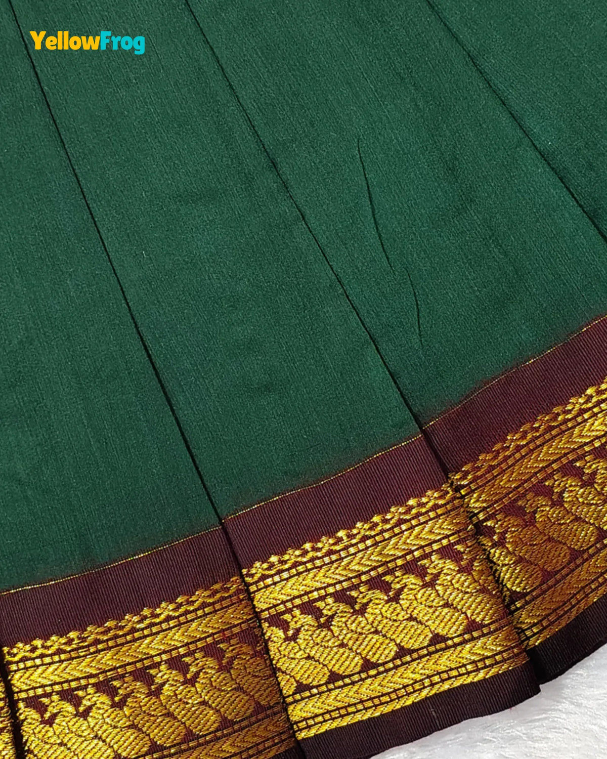 Close-up of a dark green fabric with a wide decorative border in deep maroon and gold woven pattern. A small 'YellowFrog' logo appears in the top-left corner.