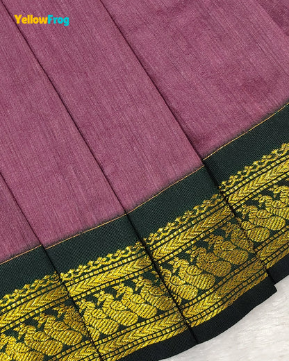 A close-up of a pleated fabric garment, likely a skirt or drape, in a muted mauve-purple color with a wide black border featuring intricate gold woven embroidery. A 'YellowFrog' brand logo is visible in the top left corner.
