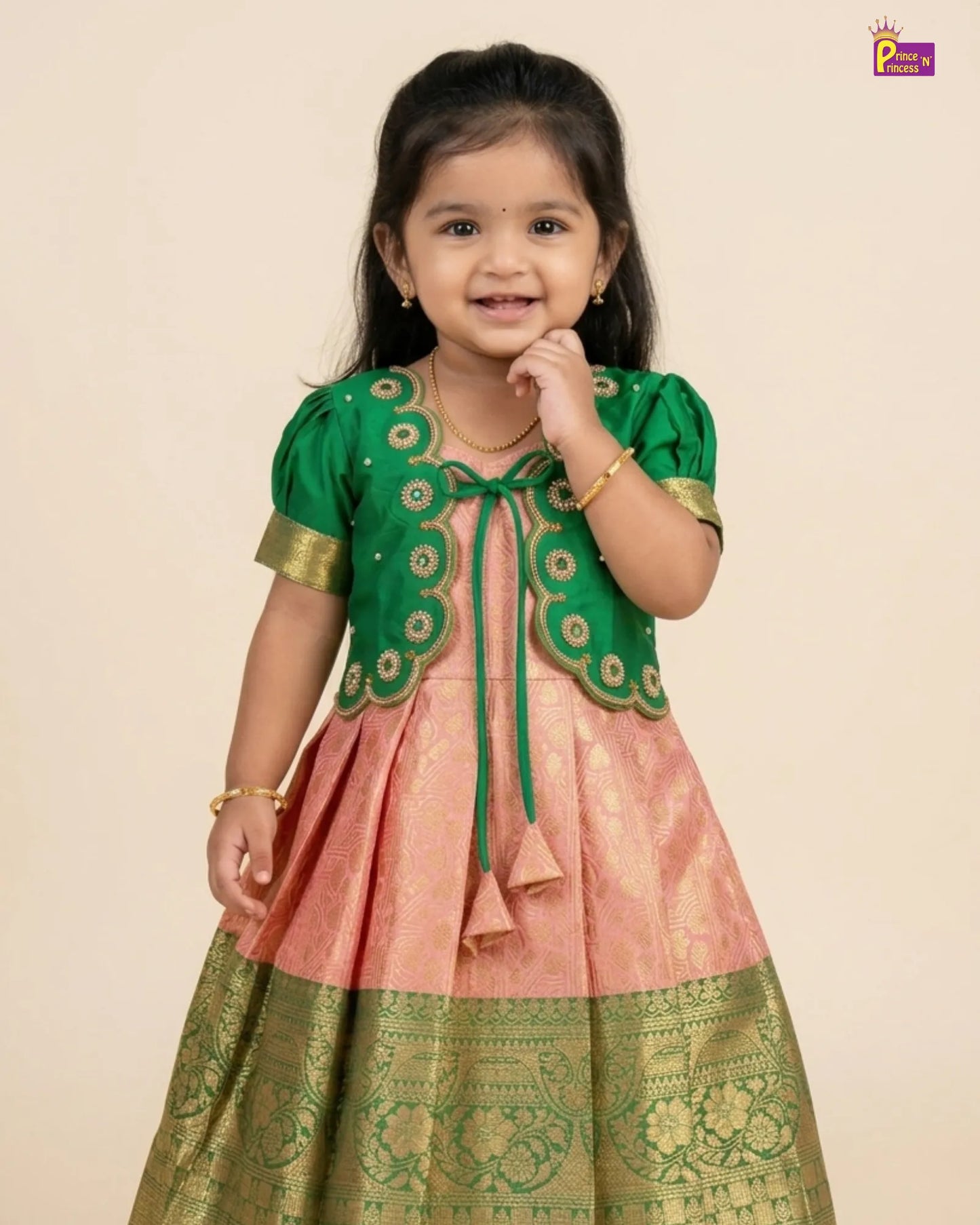 Young girl wearing a green and pink traditional outfit on a beige background