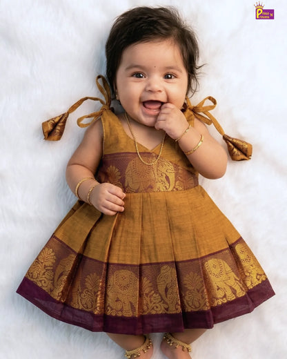 Baby wearing a traditional outfit with gold and brown colors on a white background